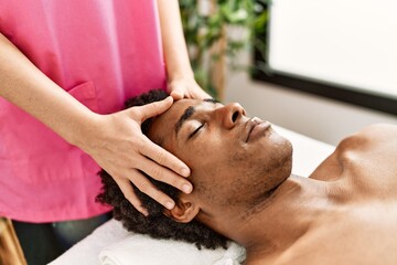 Fototapeta na wymiar Young african american man having face massage at beauty center