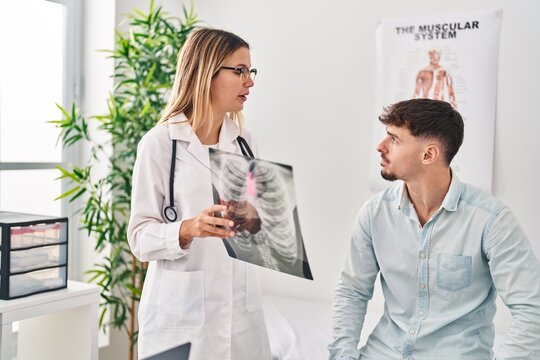 Young man and woman doctor and patient having medical consultation holding xray at clinic