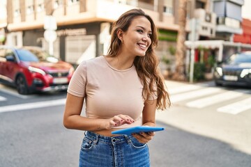 Young beautiful hispanic woman smiling confident using touchpad at street