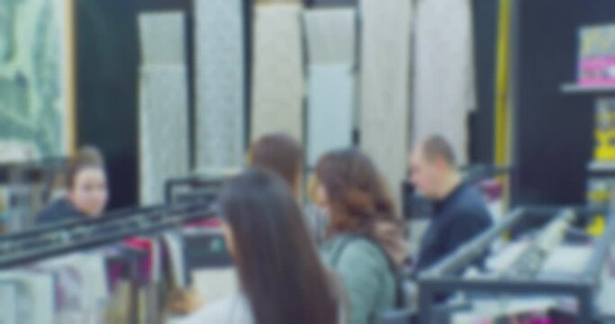 blurry defocused video. shoppers in a clothing store. silhouettes of several unrecognizable people who choose fabrics in a shop.