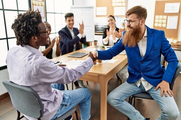 Obraz premium Group of business workers smiling and clapping to partners handshake at the office.