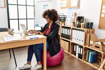 Young african american woman smiling confident working sitting on fit ball at office