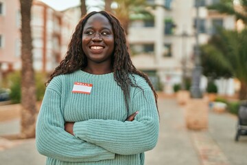 Young african woman smiling happy wearing hello i am sticker at the city