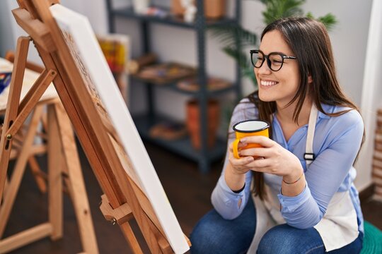 Young woman artist drinking coffee at art studio