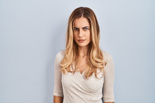 Young blonde woman standing over isolated background skeptic and nervous, frowning upset because of problem. negative person.