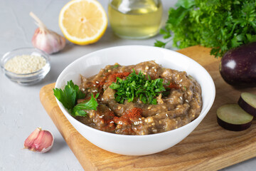 Baba ghanoush or eggplant hummus in white bowl on wooden board, traditional Middle Eastern cuisine
