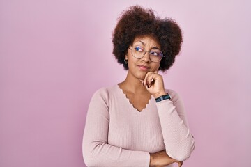 Young african american woman standing over pink background thinking worried about a question, concerned and nervous with hand on chin