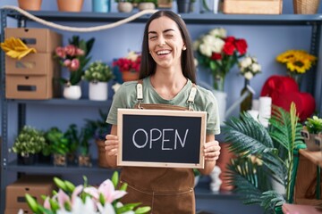 Young brunette woman working at florist holding open sign winking looking at the camera with sexy...