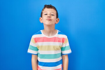 Young caucasian kid standing over blue background looking at the camera blowing a kiss on air being lovely and sexy. love expression.