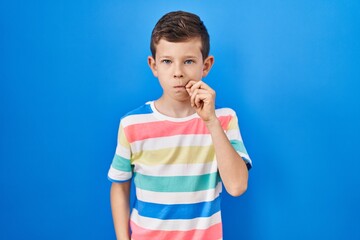 Young caucasian kid standing over blue background mouth and lips shut as zip with fingers. secret and silent, taboo talking