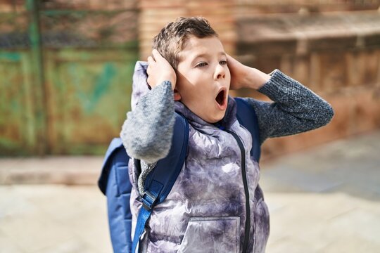Blond child student standing with surprise expression at street