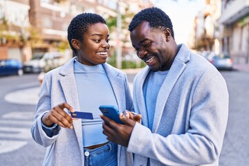 Man and woman couple using smartphone and credit card at street