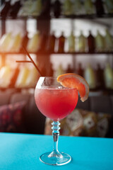 red grapefruit juicy cocktail with straw in bar, cafe or restaurant on table