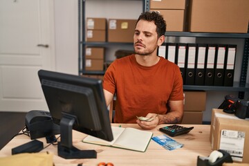 Young hispanic man ecommerce business worker counting chile pesos banknotes at office