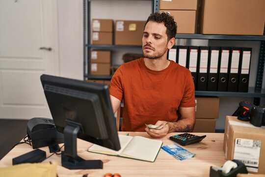 Young hispanic man ecommerce business worker counting chile pesos banknotes at office