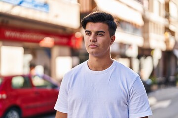 Fototapeta premium Young hispanic man looking to the side with serious expression at street