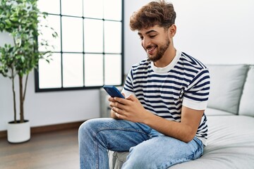 Young arab man smiling confident using smartphone at home