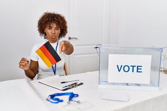 Young african american woman at political campaign election holding germany flag pointing with finger to the camera and to you, confident gesture looking serious