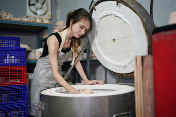 Fototapeta premium Young creative woman small business owner work in art studio with pottery for handmade shop. Girl relax with painting, ceramics after work create craft kitchenware in workshop. Artistic hobby