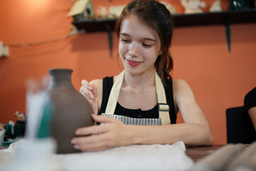Pottery craft master showing her disciple how to make workpieces for earthenware