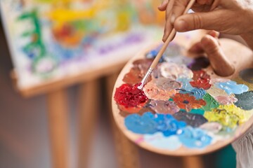 Middle age woman artist mixing color on palette at art studio