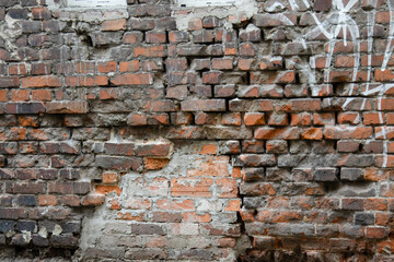 Texture of a cracked brick wall of an old crumbling house. Cracks in brick facade