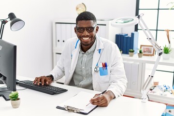 Naklejka na ściany i meble Young african american man wearing doctor uniform working at clinic