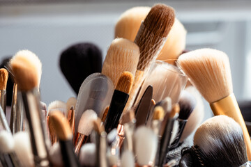 many different makeup brushes on a sunny windowsill, makeup artist's equipment