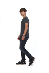 side view of a a full portrait of a teenager walking on white background and looking at camera,serious