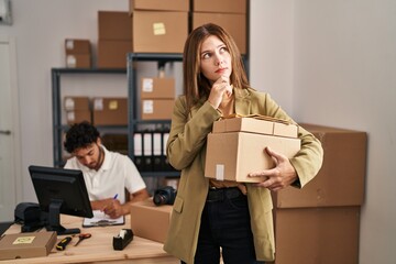 Young two people working at small business ecommerce serious face thinking about question with hand on chin, thoughtful about confusing idea