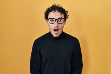 Obraz premium Hispanic man standing over yellow background afraid and shocked with surprise and amazed expression, fear and excited face.