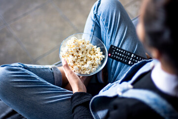 Top view of a person eating popcorn watching TV