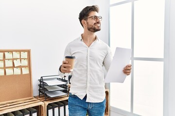 Young hispanic businessman drinking coffee working at the office.