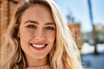 Young blonde woman smiling at the city