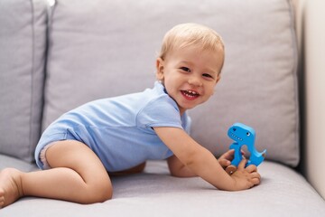 Adorable toddler playing with toy sitting on sofa at home
