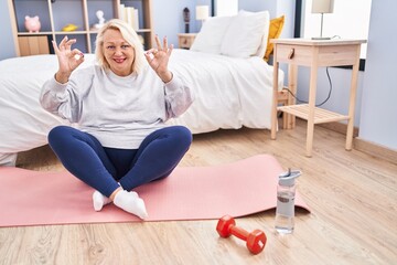 Middle age blonde woman doing yoga exercise at bedroom