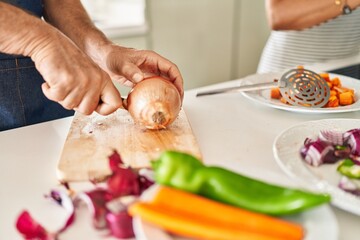 Middle age hispanic couple cooking at kitchen