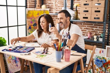 Middle age man and woman artists drawing on notebook at art studio