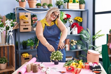 Young woman florist talking on smartphone cutting flower at florist