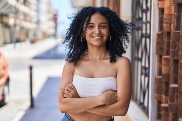 Young hispanic woman smiling confident standing with arms crossed gesture at street