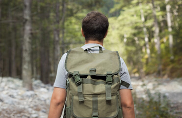 Close up hiking man from behind with his tourist backpack is walking in a forest. Healthy lifestyle...