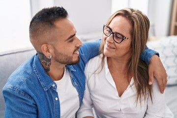 Man and woman mother and son hugging each other sitting on sofa at home