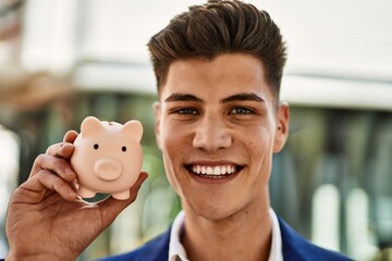 Young man wearing suit holding piggy bank at street