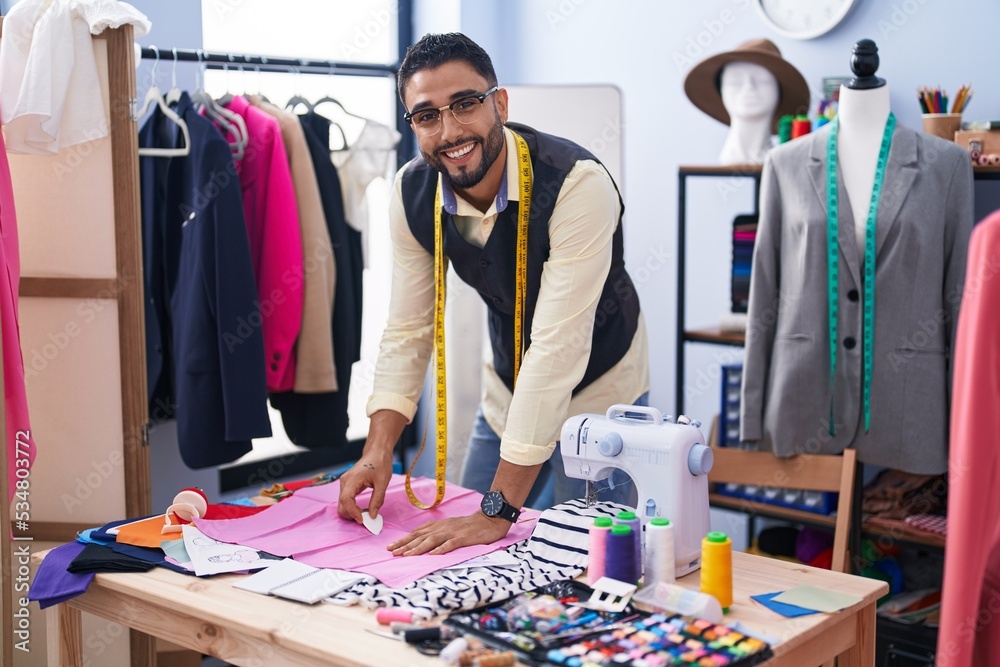 Sticker Young arab man tailor smiling confident make mark on cloth at clothing factory