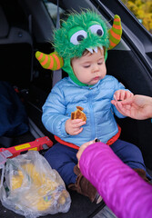 Tailgating baby monster is having some snacks in the back of the car on Halloween