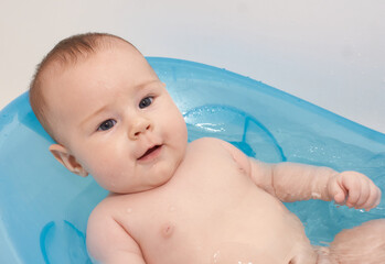 Little baby taking a bath in a blue baby tubh