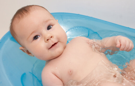 Little baby taking a bath in a blue baby tubh
