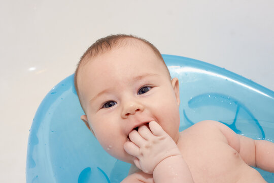 Little baby taking a bath in a blue baby tubh