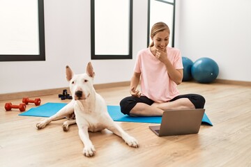 Young caucasian woman having video call with dog at sport center