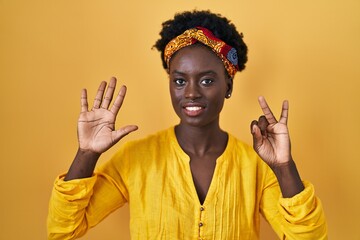 African young woman wearing african turban showing and pointing up with fingers number seven while smiling confident and happy.